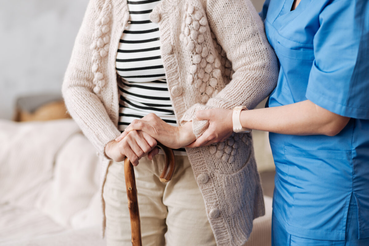 nurse holding seniors arm, helping